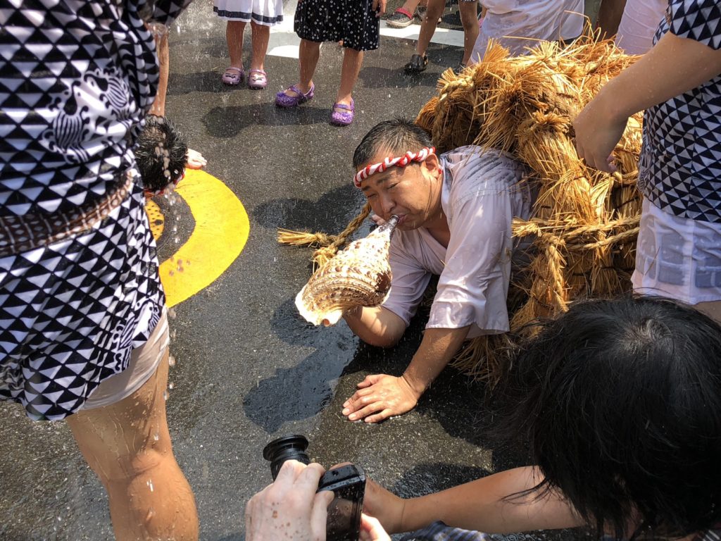 わらに巻かれた男が水をかけられ法螺貝を鳴らす!?奇祭”水止舞”